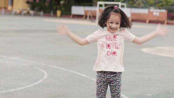 可爱的亚洲女孩在孩子和孩子夏天的时候在学校操场上跳着锻炼她的微笑表现出积极的情绪快乐幸福和快乐