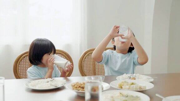 亚洲家庭关系兄弟姐妹在早餐桌上争夺牛奶