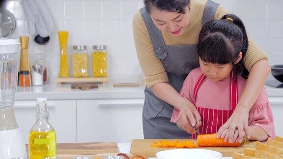 一个快乐的年轻家庭妈妈爸爸和小女孩在厨房里一起做饭