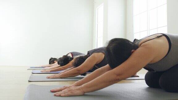 一群亚洲女性多代伸展运动和练习瑜伽在健身房锻炼