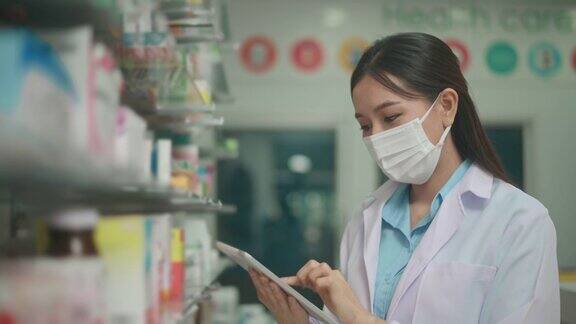 一位女性药剂师穿着实验服和防护口罩在一家现代药店使用药片分析医疗数据