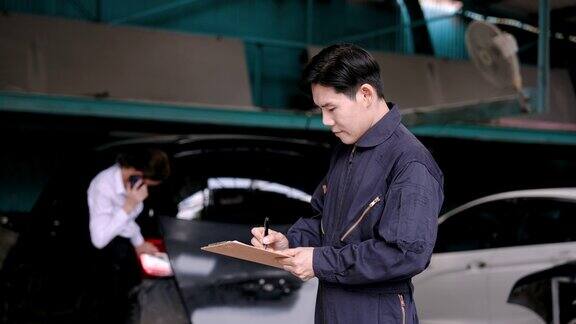 亚洲保险从业人员身穿技工服手持文件检查发生事故的汽车状况准备估算修理汽车的费用
