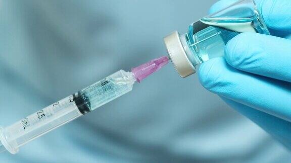 在医院里医生的手拿着注射器和蓝色的疫苗瓶健康和医学概念