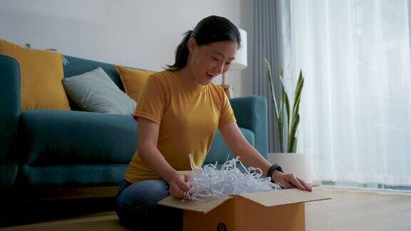 一名亚洲妇女打开网上购物的纸箱打开包装并检查产品