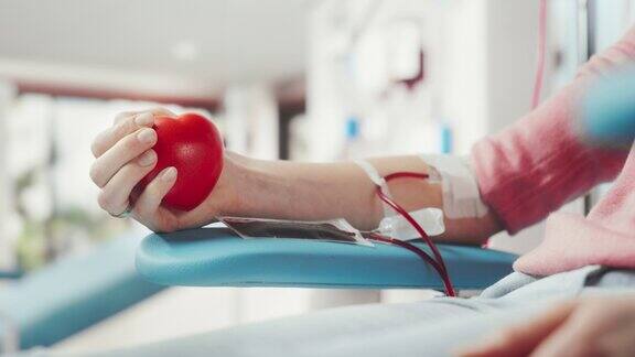 女性献血者的手的特写镜头白人妇女挤压心形红球将血液通过管道泵入袋中器官移植病人的捐赠