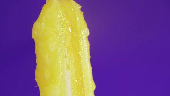 将蜂蜜糖浆倒在黄色紫色背景的冰淇淋上