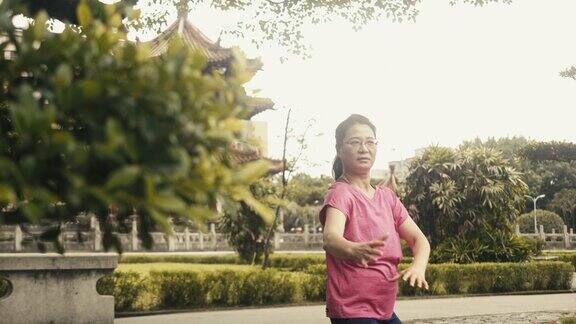 活跃的亚洲资深女性在公园里打太极(慢动作)