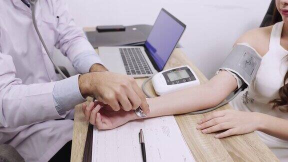 手持医生测量病人的压力医护人员检查血压的年轻妇女期间