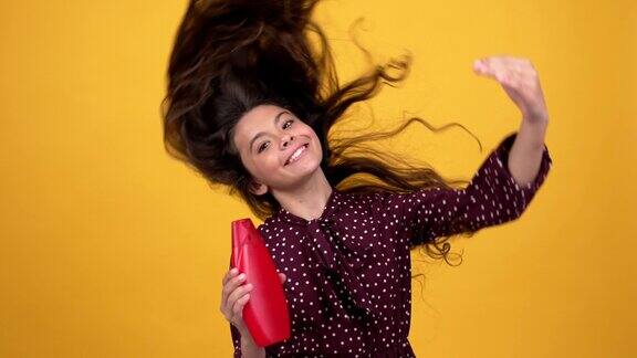 快乐少女挥动她的长美丽健康波浪发广告护发素瓶调理头发