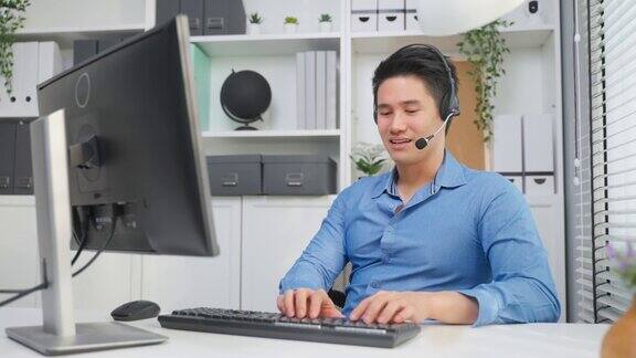 亚洲英俊的商人使用笔记本电脑在办公室工作有吸引力的专业男性员工坐在桌子上感到快乐享受在公司工作场所的休闲时间