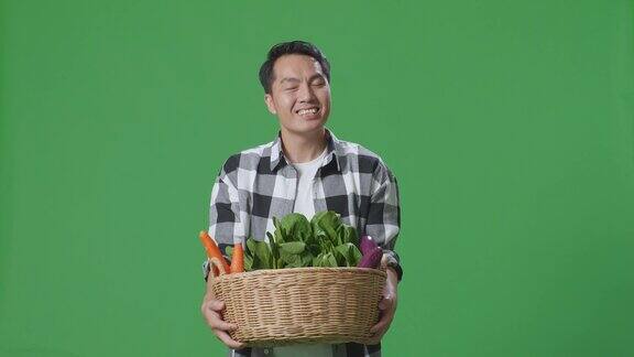 亚洲男农民提着菜篮走在摄影棚的绿幕背景上