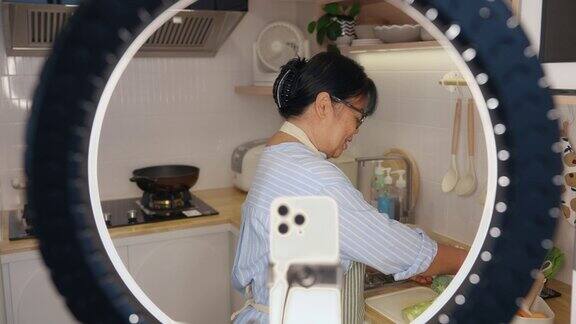 亚洲女人在厨房用智能手机录视频