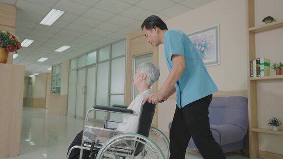 男护理助理坐在轮椅上关心地与病人交谈在医院或诊所