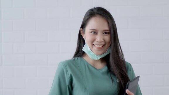 快乐友好的亚洲医生外科医生戴着摘下外科口罩微笑用平板技术专业专业的医疗保健安全保护新冠肺炎大流行