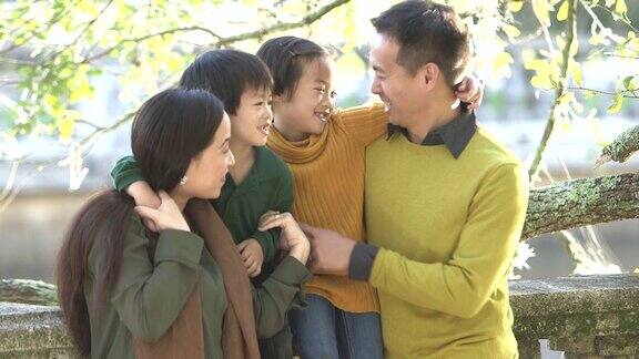一个亚洲家庭带着两个孩子在公园里