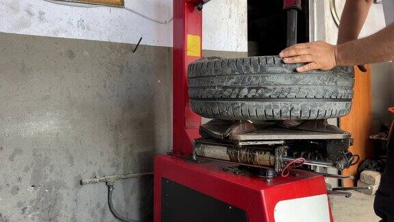 在汽车维修服务中心的车库里机械师的手推着汽车轮胎