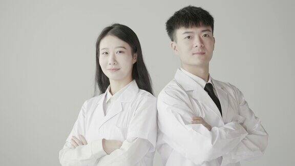 美丽的女医生和男医生背靠背站着对着镜头微笑亚洲医生整形医生慢动作拍摄