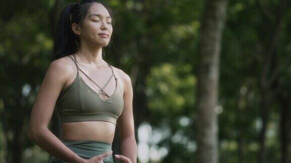 周末早上一名亚裔华裔妇女在公园里冥想练习瑜伽