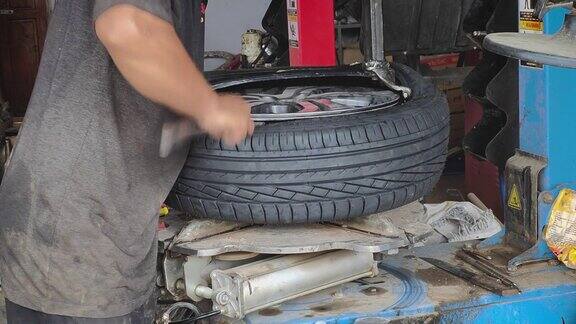 汽车修理工在车库里用自动机器把轮胎从车轮上扯下来换轮胎