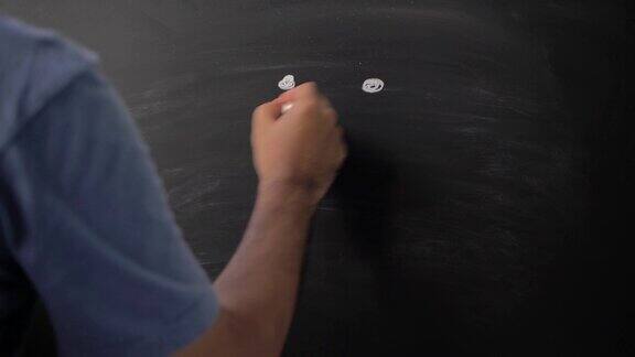近男手用粉笔在黑板上画微笑情感图标