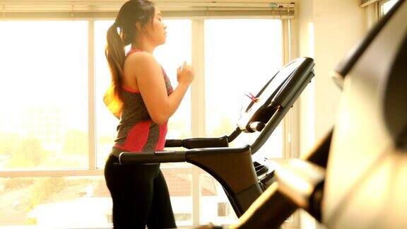 年轻的亚洲女子在跑步机上锻炼