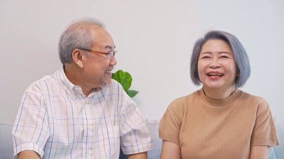 亚洲退休老人的特写或特写他们坐在沙发上幸福地交谈着