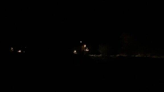 一列带着大灯的火车在夜间沿着铁轨行驶