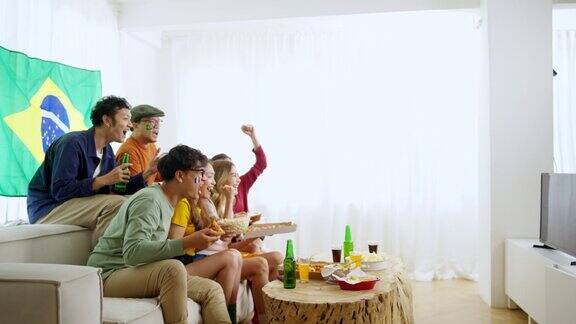 一群亚洲男女朋友一起在家里看电视上的足球运动