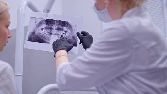 牙科医生和病人一起看口腔的x光照片牙医在x光片上显示哪些牙齿需要治疗拥有专业设备的现代化牙科诊所