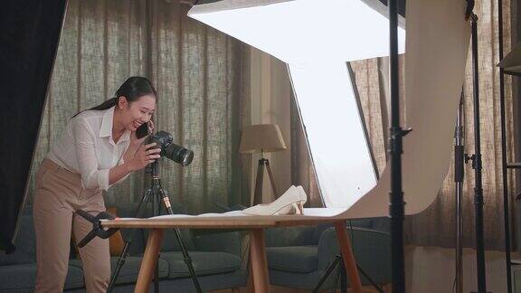 亚洲女摄影师一边用智能手机一边在家庭工作室拍摄女鞋