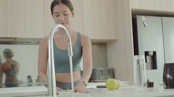 年轻的亚洲女性在锻炼后制作绿色排毒奶昔健康的生活方式
