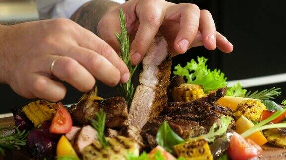 烤的肉厨师用迷迭香装饰烤肉和蔬菜