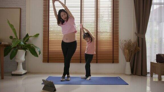 孕妇在家和女儿做瑜伽