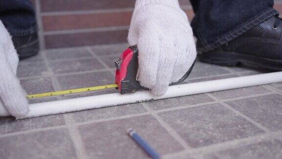近照男电工的手正在用卷尺测量白色塑料管的长度