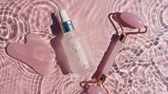 化妆品瓶与移液管在粉红色的背景与水滴纯净水反射阳光和阴影缓慢运动的波浪水一款保湿护肤品的广告