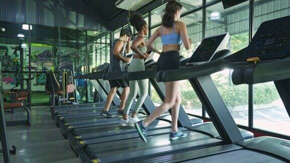 穿着运动服的各种青年运动员正在健身馆的跑步机上跑步