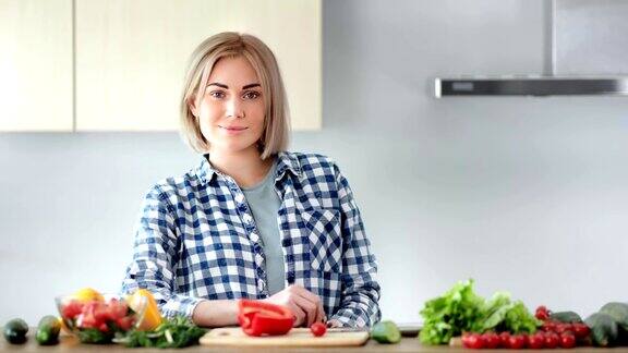 美丽年轻的家庭主妇在厨房摆姿势烹饪健康的食物看着镜头