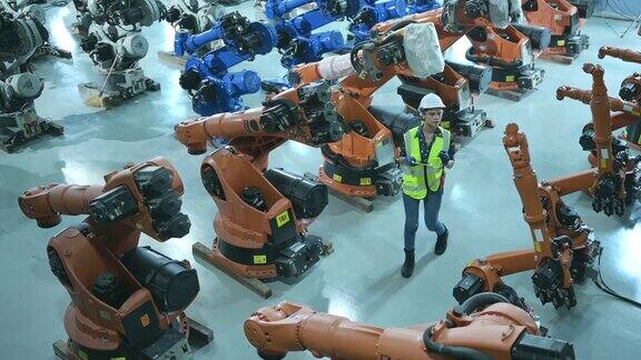 一名女工程师在机器人仓库的机器人手臂上安装程序并在送机给客户前进行操作测试