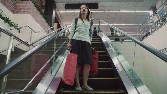 带着旅行袋的女人在机场航站楼的自动扶梯上