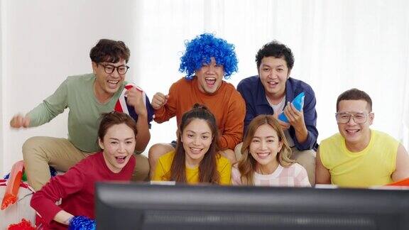 一群亚洲男女朋友一起在家看电视上的体育比赛