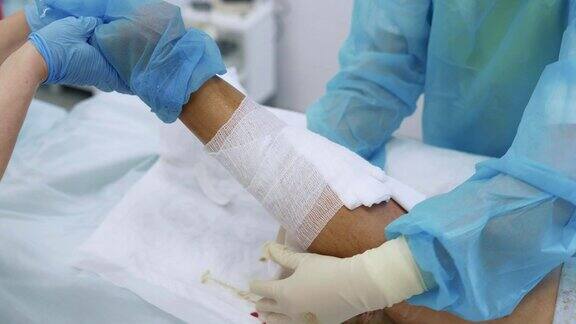 静脉曲张切除手术后外科医生双手用无菌手套包扎病人腿部