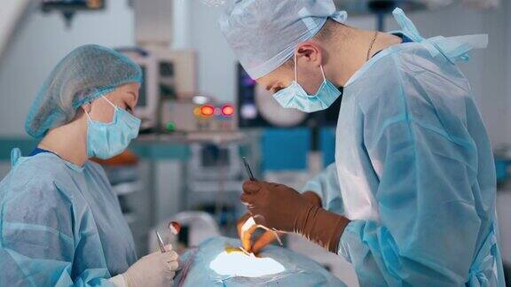 医生和女助手进行手术年轻的外科医生和护士在手术中对现代医疗设备的临床背景