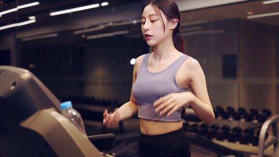 年轻的亚洲女子在健身房的跑步机上锻炼