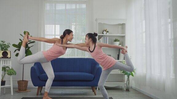 母女俩正在家里练习瑜伽舞者式或Natarajasana