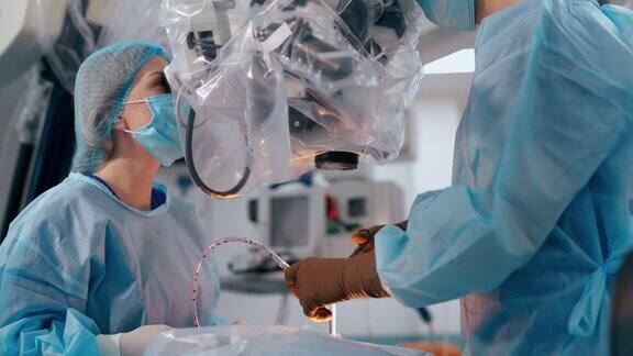 外科医生使用手术显微镜医生和助手在医院的手术室里使用现代化的医疗设备