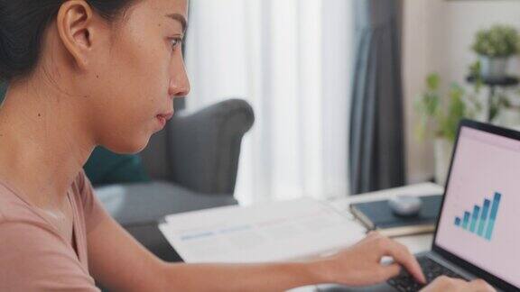 自由亚洲女士休闲服装使用笔记本电脑在家里的客厅在线学习