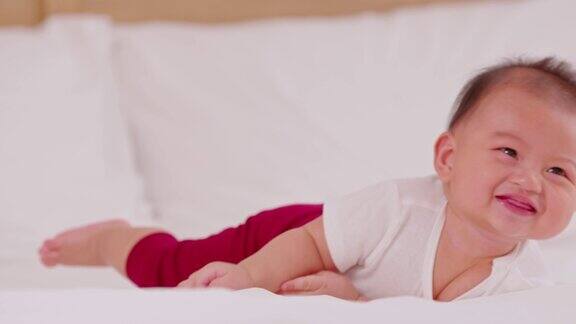 新生婴儿平躺在床上发展颈部控制腹部时间加强婴儿颈部和肩部肌肉可爱的婴儿躺在白色的床上爬行幸福和乐趣肚子上的时间