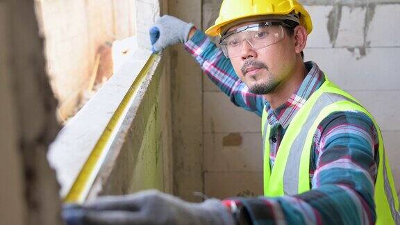 亚洲男建筑工人用工具施工卷尺检查房屋窗台的距离