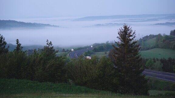 清晨的景色从山到山森林和公路在雾中