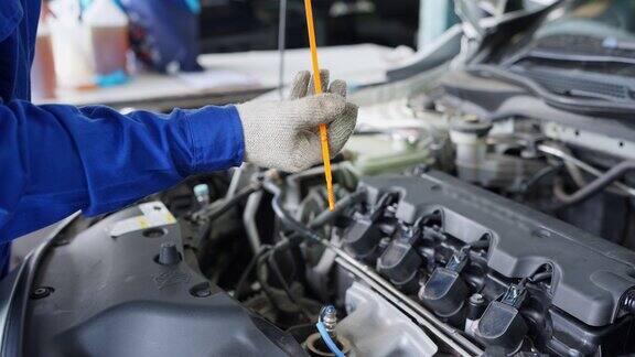 按规定的时间间隔更换发动机油使发动机清洁如新汽车机械工人在汽车修理厂用油尺检查油箱内机油的油位